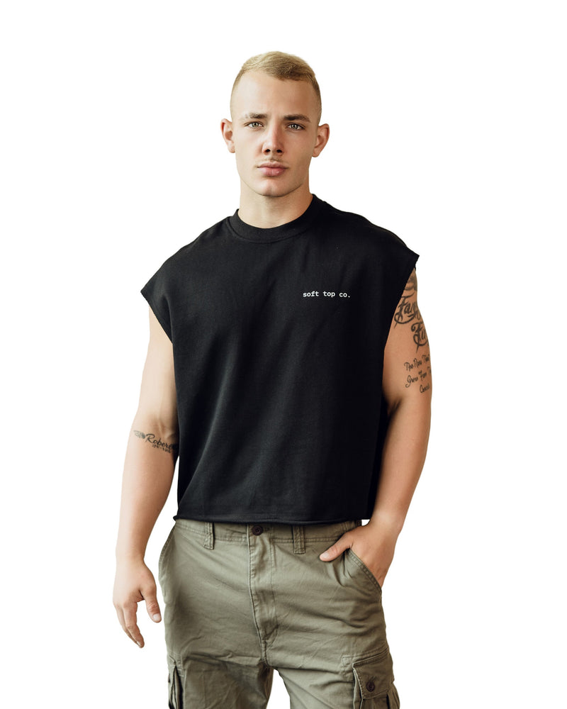 Model wearing a black sleeveless Soft Top Co. tank with small white “soft top co.” chest logo, paired with cargo pants, standing against a clean white background.